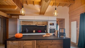 Cocina moderna con detalles de madera, una isla central e iluminación colgante.