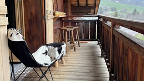 Una terraza de madera con una silla y una mesa, con vistas a un paisaje pintoresco.