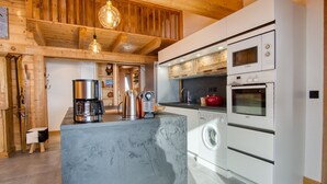 Una cocina moderna con una isla central, electrodomésticos integrados y vigas de madera en el techo.