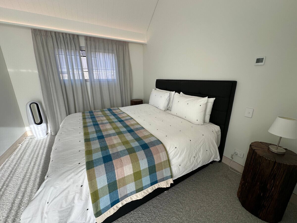 A hotel room with a bed, curtains, a bedside table, and a lamp.