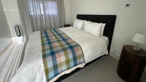 Une chambre d’hôtel avec un lit, des rideaux, une table de chevet et une lampe.
