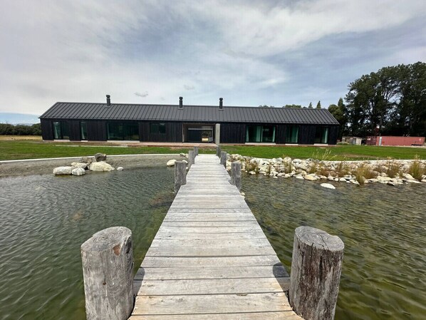 A wooden dock leading to a modern building with a dark roof.