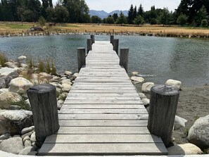 A wooden pier leading into a lake, surrounded by rocks and trees.