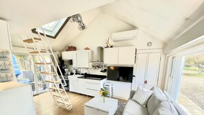 Ett modernt boende i loftstil med kök, matplats och en mysig sittgrupp.