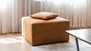 A square ottoman with a cushion in a room with wooden flooring and a large window with sheer curtains. - 2-BR Apartment close to Radio Shkodra: Roger That! by PikHost (Shkodër)