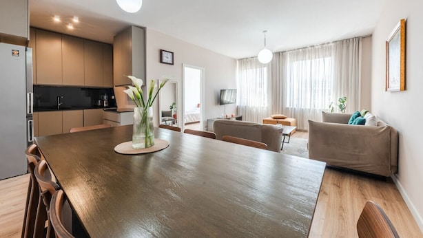 A modern apartment with a wooden dining table, a sofa, and a kitchen area. - 2-BR Apartment close to Radio Shkodra: Roger That! by PikHost (Shkodër)