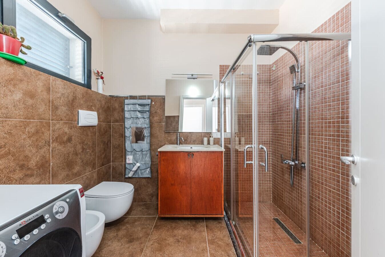 A bathroom with a shower, toilet, and a washing machine.
