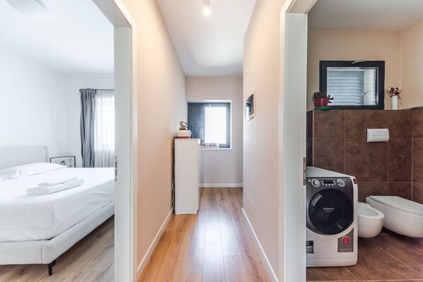 Una habitación de hotel con cama, una ventana pequeña, un baño con lavadora e inodoro.