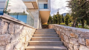 Una escalera conduce a un edificio moderno con paredes de piedra y barandillas de vidrio.