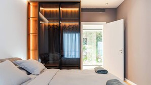 Un dormitorio con cama, armario y puerta que da a un balcón.
