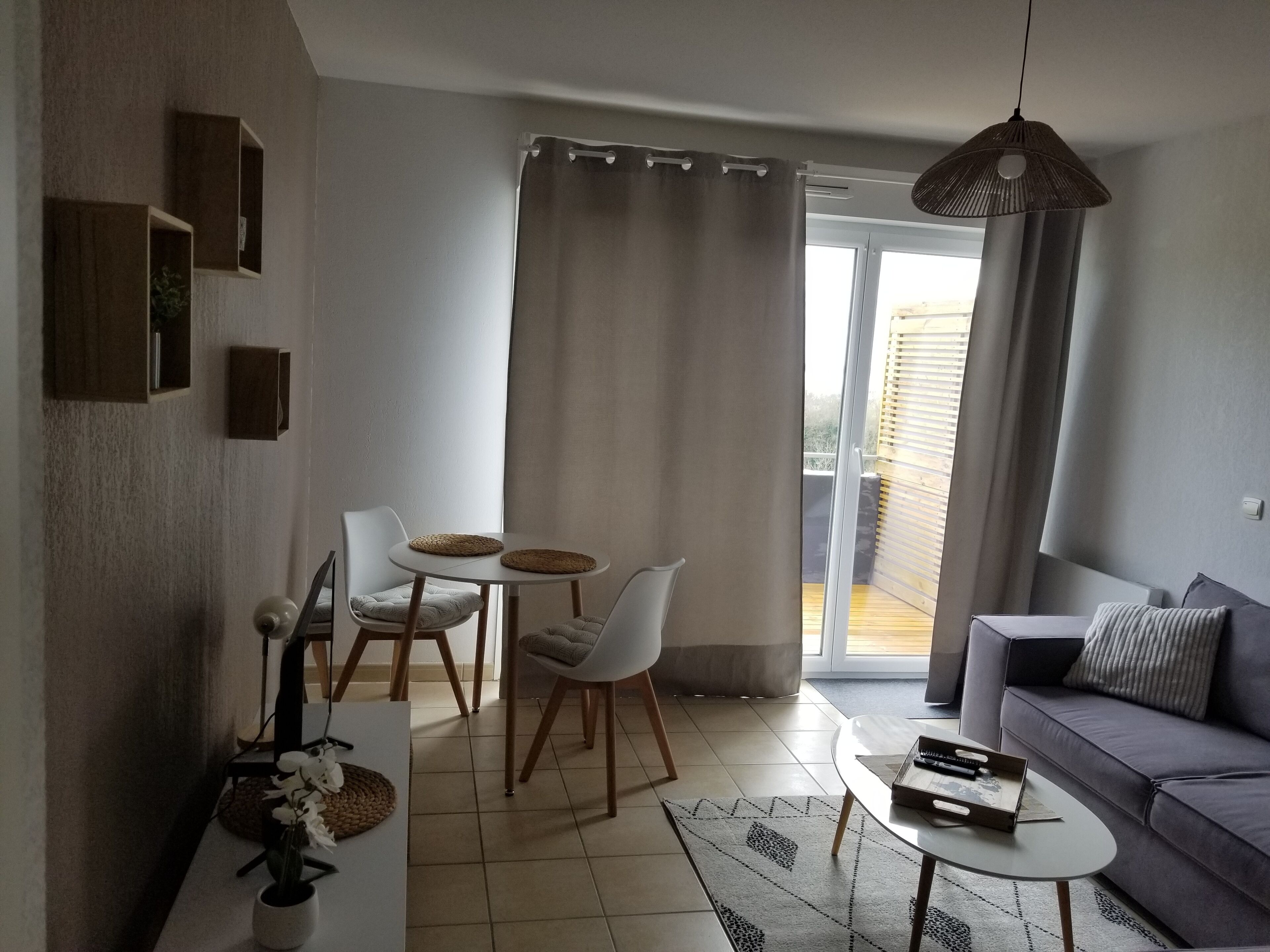 Una sala de estar moderna con un sofá, una mesa de comedor con sillas, una mesa de centro y una lámpara colgante.