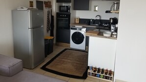 Eine kleine Küche mit Kühlschrank, Backofen, Mikrowelle und Waschmaschine.