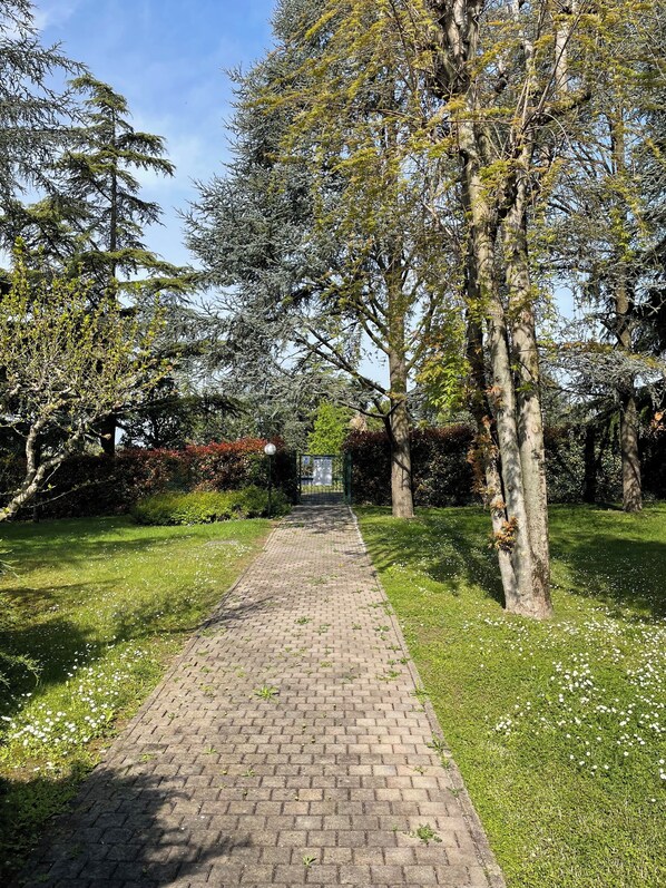 A paved pathway in a park with trees and grass on either side. - Oasis of Relaxation in Punta Grò - Two-room apartment with Pool and Nearby Beach (Sirmione)