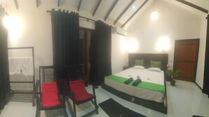 A bedroom with a bed, a chair, a small table, and a window with curtains.