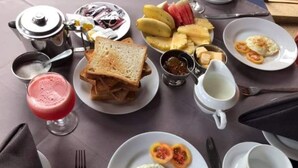 A breakfast setting with toast, eggs, fruit, and a coffee pot.
