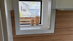 Una ventana pequeña con vista a una casa y árboles.