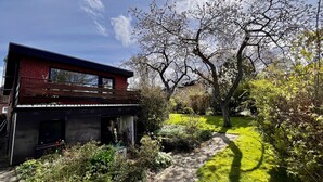 Una casa moderna con fachada de ladrillo, garaje a la vista y un jardín bien cuidado con diversas plantas y césped.