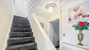 A staircase with a modern design, a chandelier, and a decorative wall piece. - Spacious family house close to beach and amenities. (Clacton on Sea)