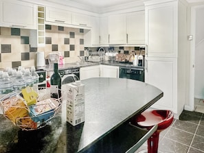 A modern kitchen with white cabinets, a black countertop, and a checkered backsplash.