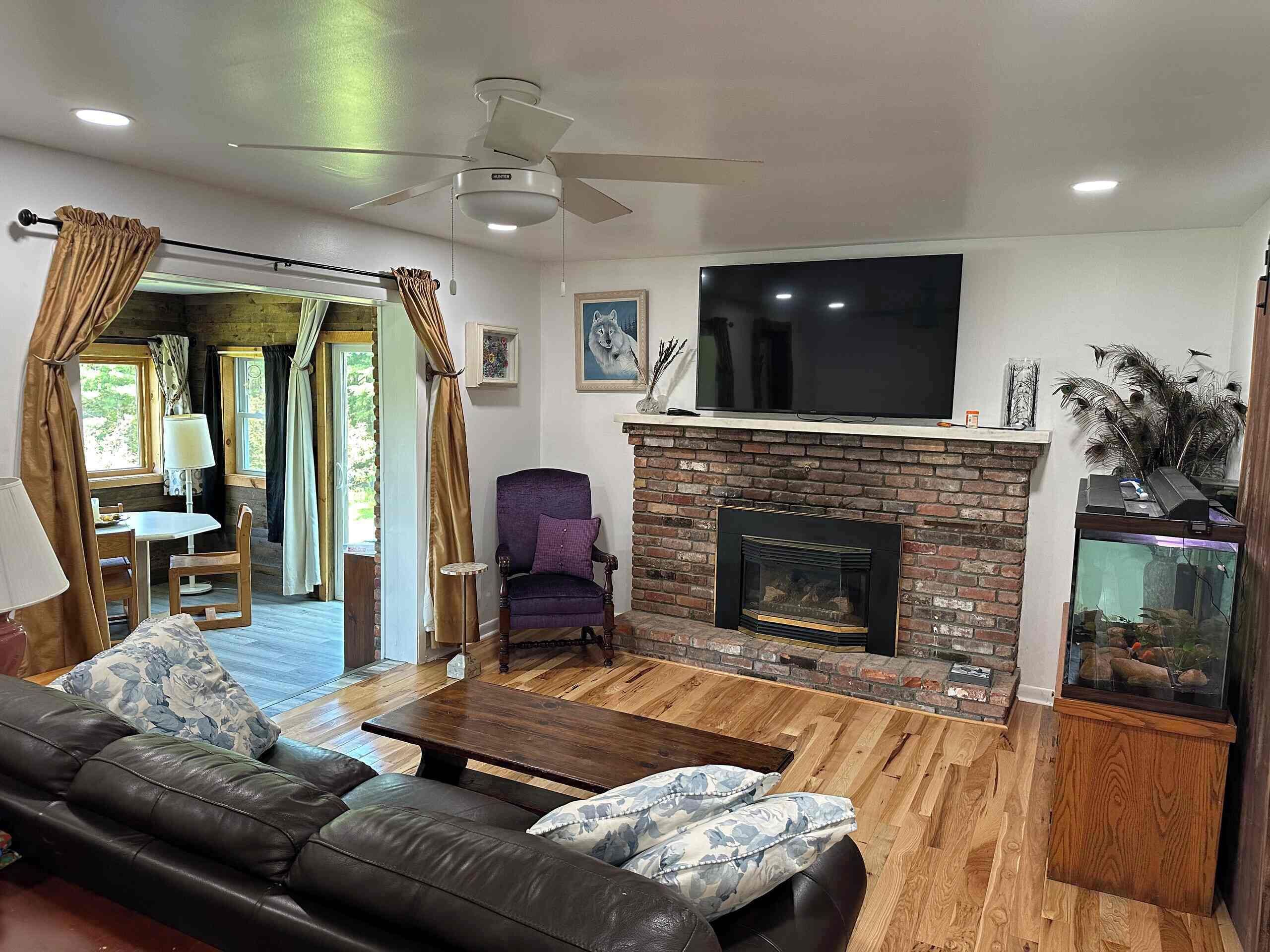 A living room with a fireplace, a television, a sofa, and a dining area.