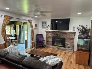 A living room with a fireplace, a television, a sofa, and a dining area.