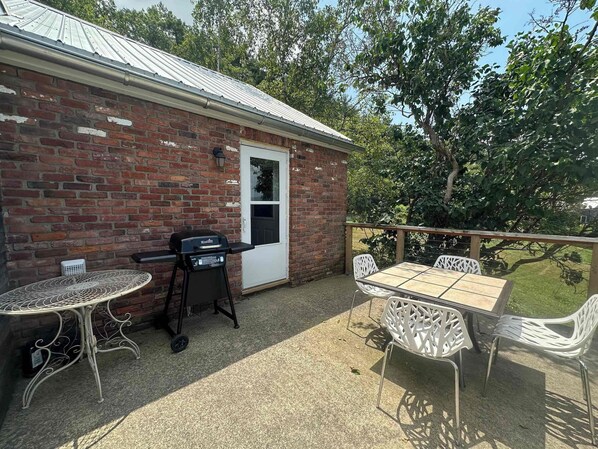 A patio area with a brick building, a grill, and outdoor furniture.