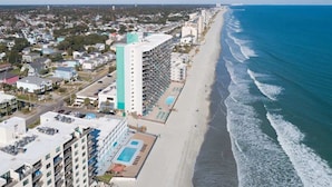 Ein Hotel an der Küste mit mehreren Etagen, einem Poolbereich und Blick auf den Strand.