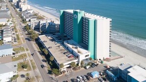 Ein hoch aufragendes Hotel mit einer markanten Fassade in Türkis und Weiß, direkt neben einem Strand gelegen.