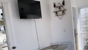Un coin repas comprenant une table et des chaises, un téléviseur fixé au mur et un élément décoratif mural.
