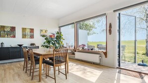 A spacious dining area with a wooden table and chairs, large windows offering a view of a green field, and artwork on the walls. - Stunning home in Gørlev with WiFi (Gørlev)