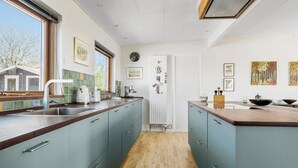 A modern kitchen with teal cabinets, a wooden countertop, and a view of the outdoors. - Stunning home in Gørlev with WiFi (Gørlev)