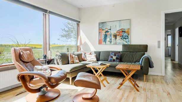 A modern living room with a large window, a sofa, a coffee table, and a recliner. - Stunning home in Gørlev with WiFi (Gørlev)