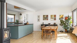 A modern kitchen with a central island, wooden dining table, and chairs. There is a stove on the left and a window above the sink. - Stunning home in Gørlev with WiFi (Gørlev)