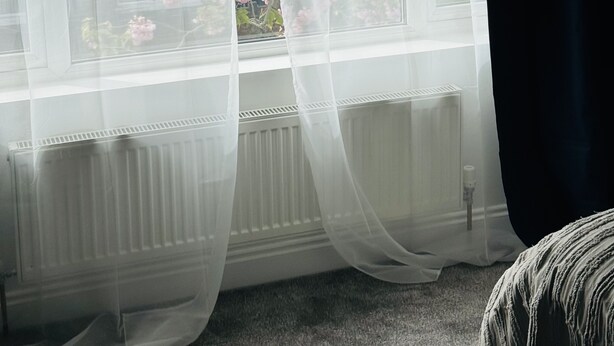 A room with a large window featuring sheer curtains, a radiator below, and a view of pink flowers outside. - Great family home to relax.
Within easy reach to London, Gatwick & Wimbledon . (Croydon)
