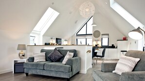 A modern loft-style living space with a high ceiling, skylights, a dining area, and a kitchen. - 3 bedroom accommodation in Westward Ho! (Westward Ho!)