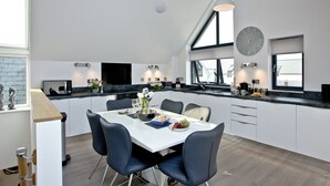 A modern kitchen with a dining area, large windows, and a clock on the wall. - 3 bedroom accommodation in Westward Ho! (Westward Ho!)