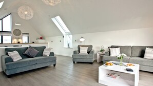 A modern living room with a grey sofa, armchairs, a coffee table, and a skylight. - 3 bedroom accommodation in Westward Ho! (Westward Ho!)