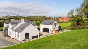 Una zona residencial moderna con casas blancas, un garaje y un césped bien cuidado.