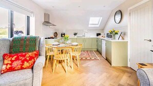 Un espacio habitable compacto con comedor, kitchenette y un ventanal que proporciona luz natural.