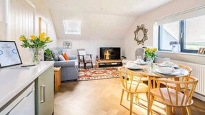 Una sala de estar moderna con sofá, televisión y comedor con sillas y una mesa.