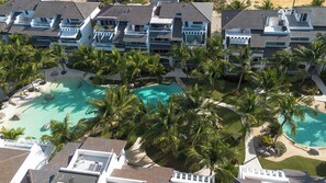 A resort with multiple swimming pools surrounded by palm trees and a large building with balconies.