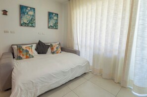 Ein Schlafzimmer mit einem Bett, einem Sofa und zwei Bildern an der Wand.