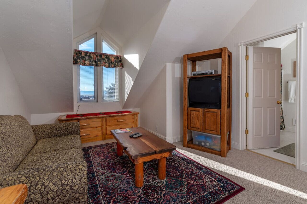 A living room with a sofa, a wooden coffee table, a TV stand, and a patterned rug.