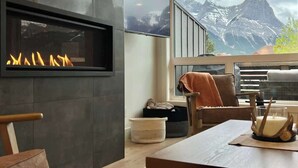 Una sala de estar moderna con chimenea, un ventanal con vistas a la montaña y un rincón de estar acogedor.