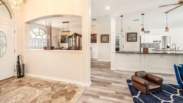 A spacious living area with a modern kitchen, a chandelier, and a blue armchair.