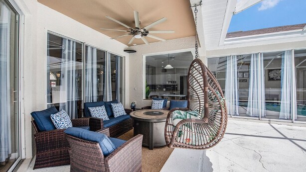 An outdoor patio with wicker furniture, a hanging chair, and a ceiling fan. - Shore Drive Sunshine fully furnished home pet friendly (Oldsmar)