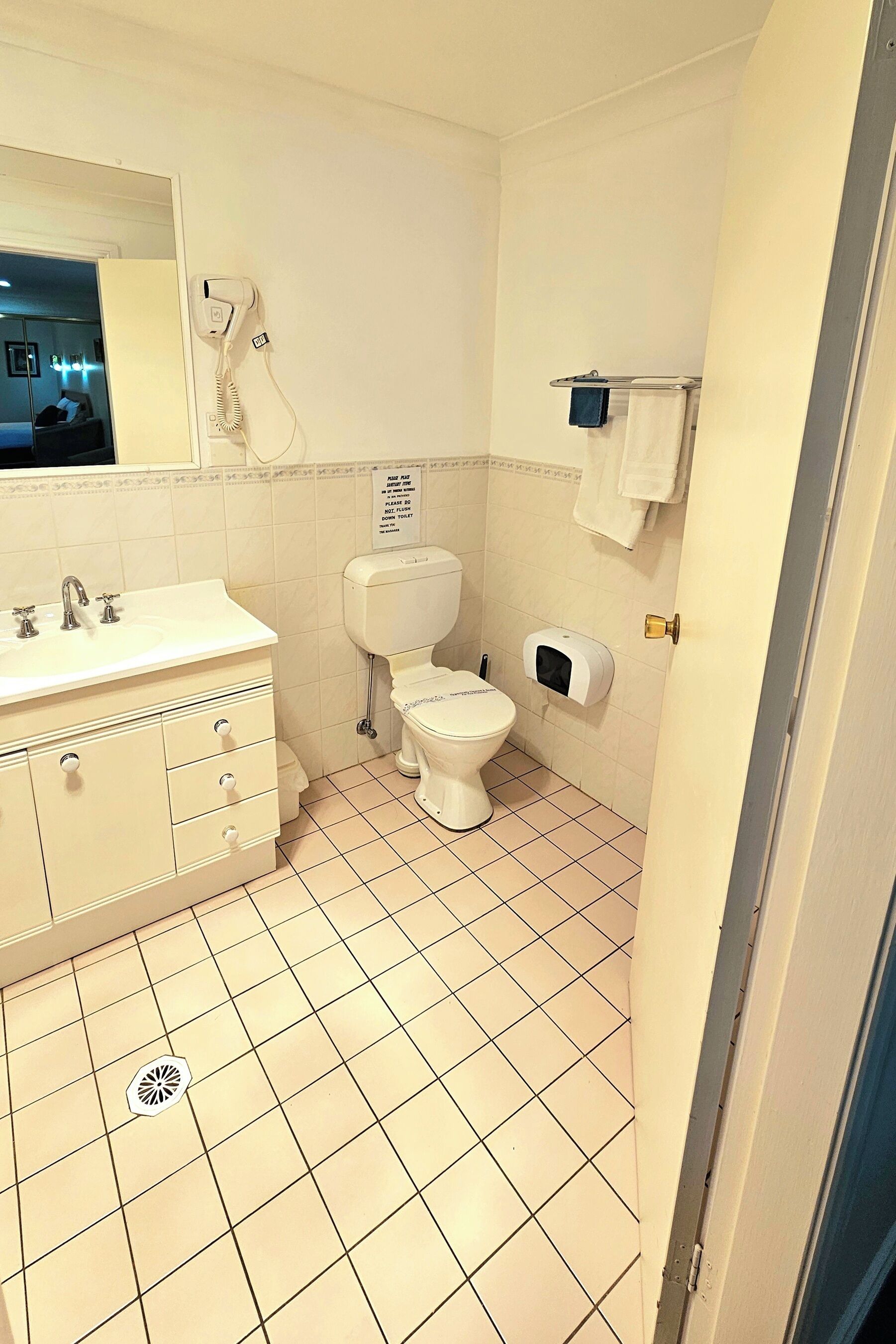 A bathroom with a white sink, toilet, and hand dryer.
