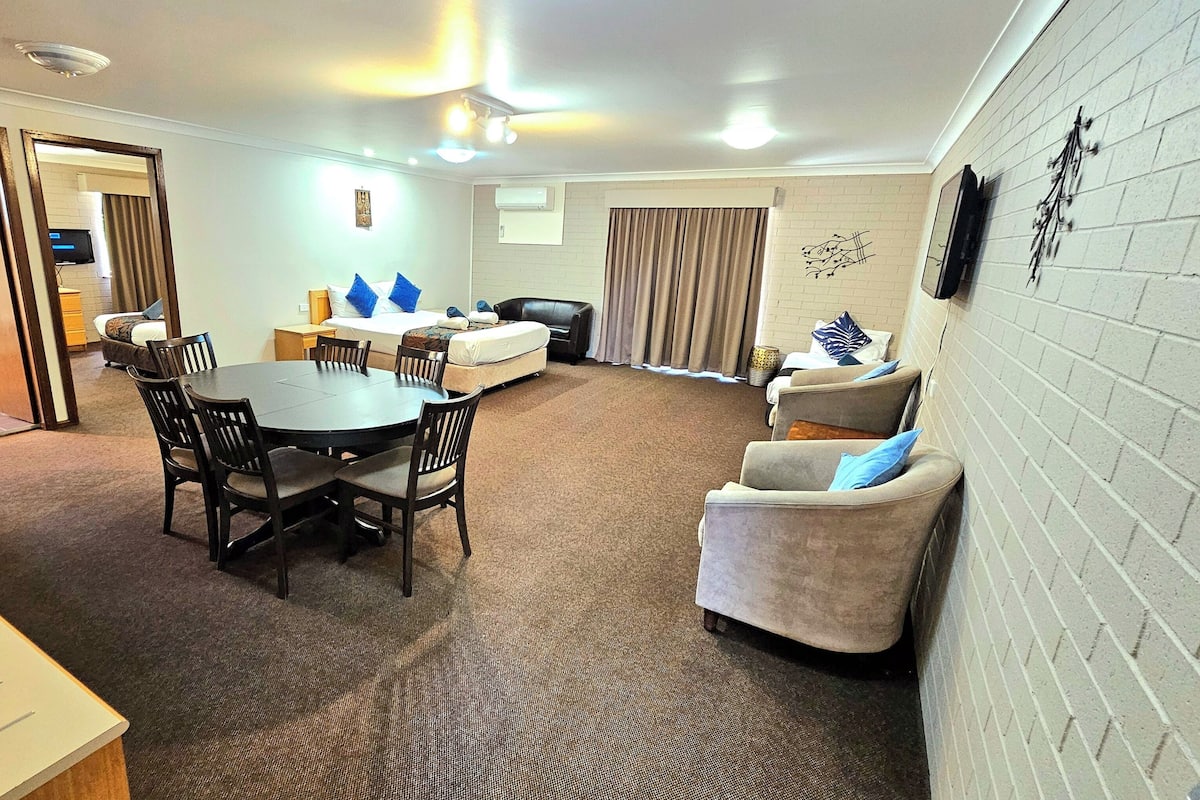 A compact living space with a dining table, chairs, a sofa, and a small couch.