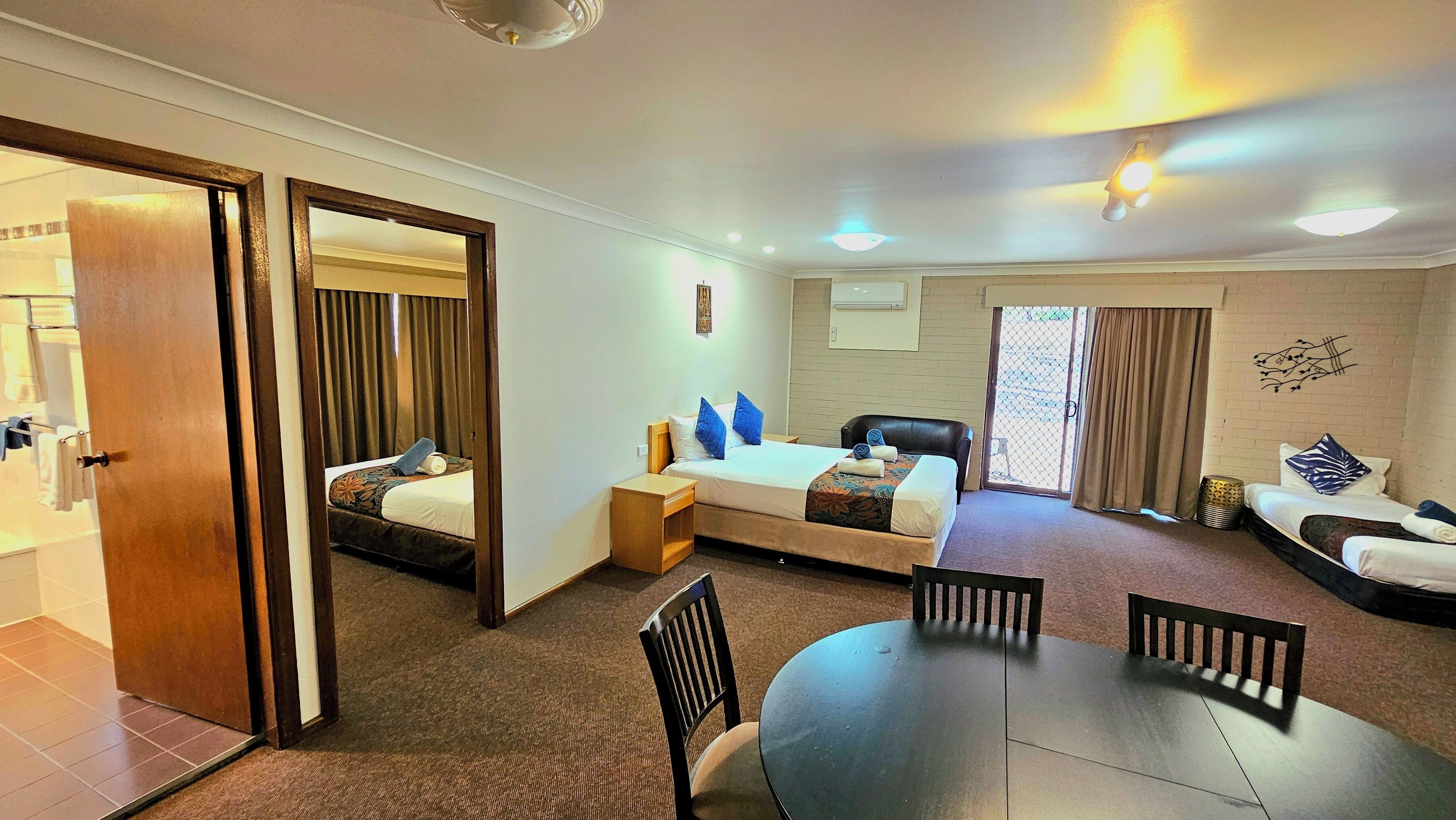 A hotel room with a bed, a sofa, a dining table, and a chair.