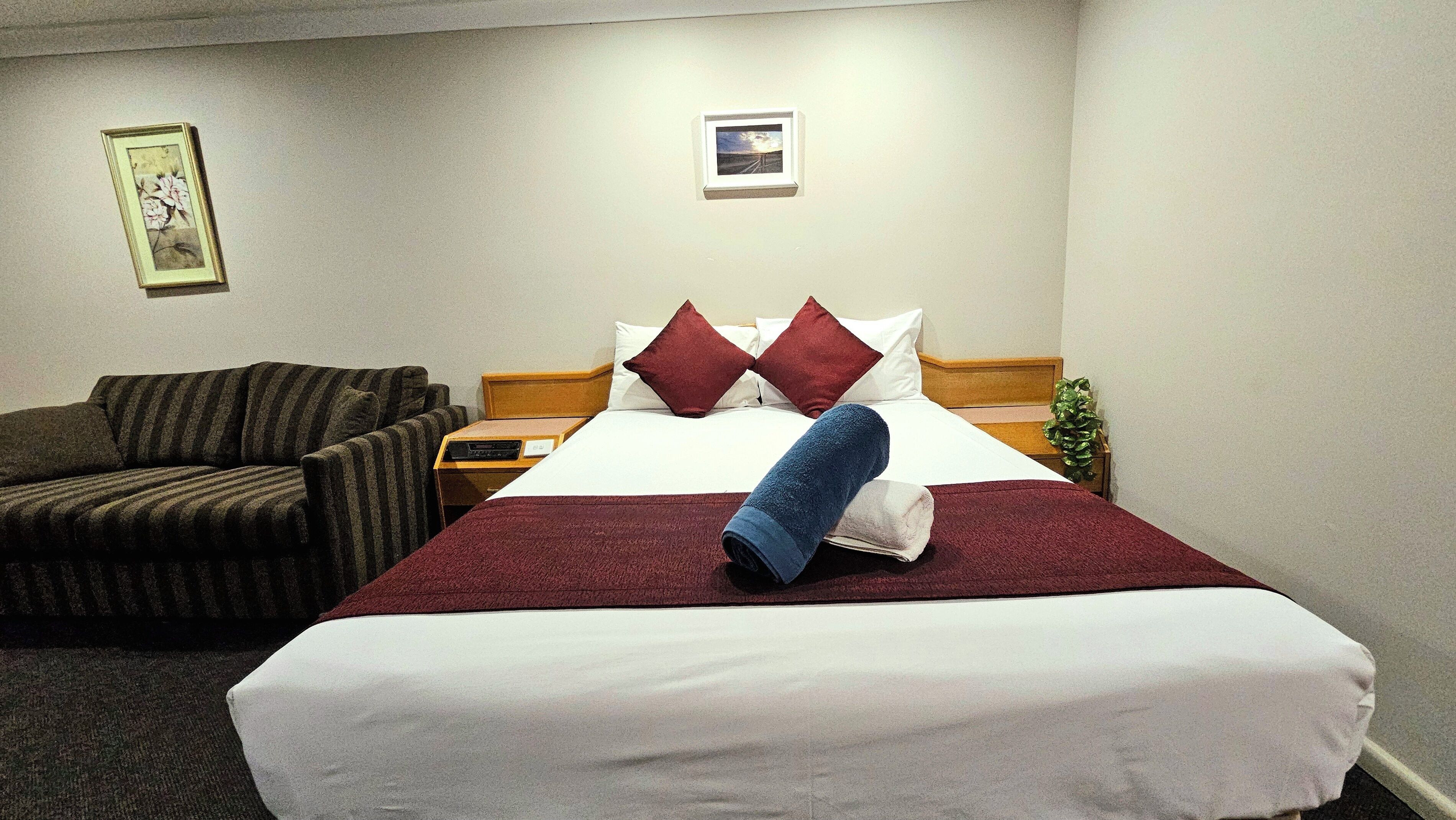 A hotel room with a bed, a sofa, a nightstand, and a small table.